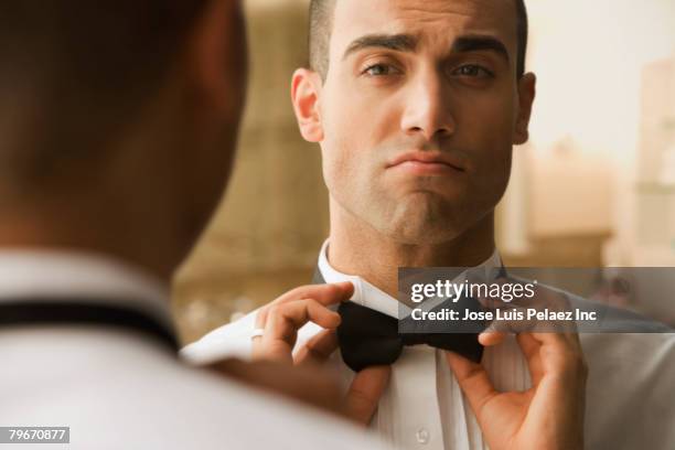 hispanic man adjusting bowtie - adjusting necktie stockfoto's en -beelden