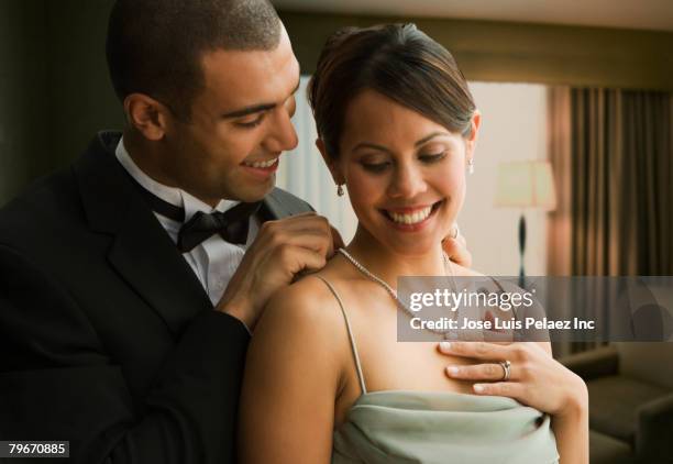 hispanic man fastening wife's necklace - couple jewelry stockfoto's en -beelden