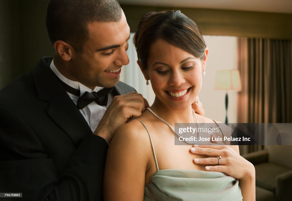 Hispanic man fastening wife's necklace