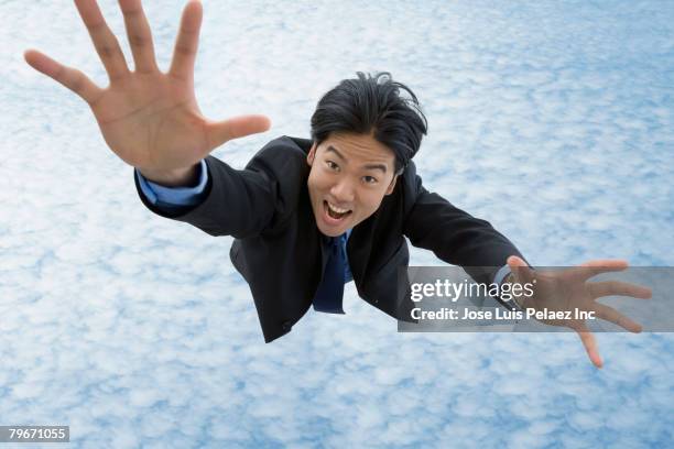 asian businessman falling in sky - arms raised ストックフォトと画像