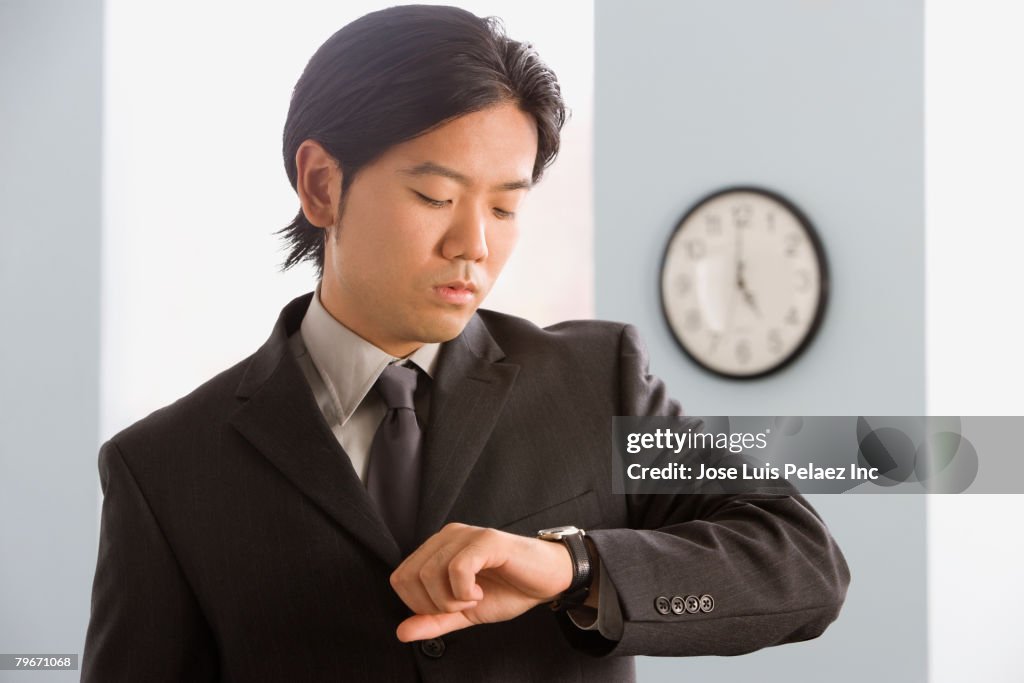Asian businessman looking at wristwatch