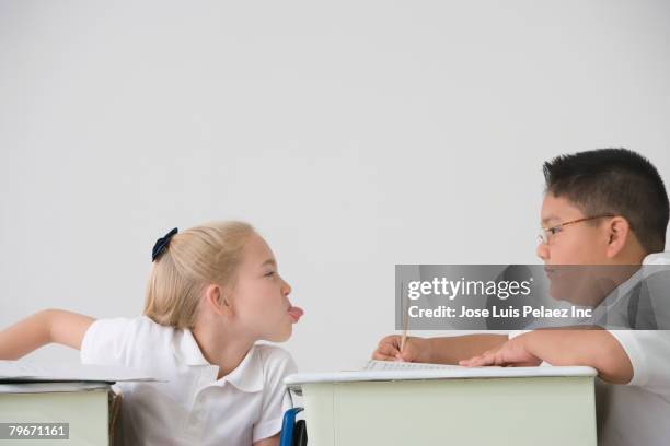 girl sticking out tongue at boy in class - human tongue foto e immagini stock