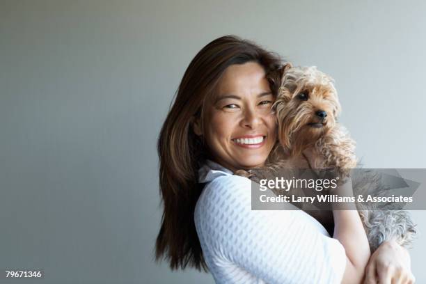 asian woman hugging dog - woman holding dog studio stock-fotos und bilder