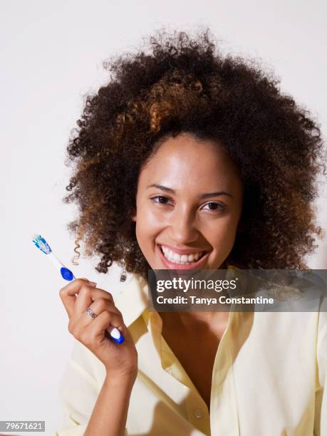 african woman holding toothbrush - una sola mujer joven fotografías e imágenes de stock