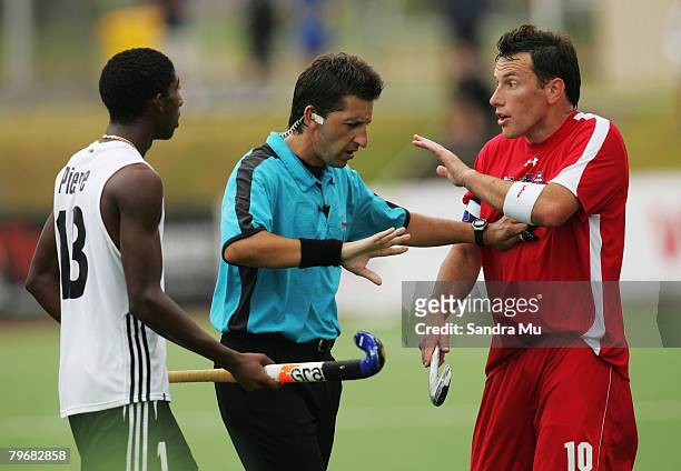 Referee Daniel Lopez talks to Pat Cota of the USA and Dwain Chan Quan of Trinidad and Tobago during the Olympic Qualifier match between the United...