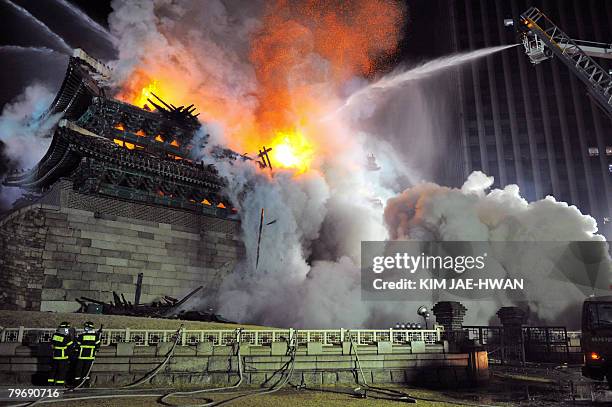 Firefighters battle a blaze at the break down Namdaemun gate, one of South Korea's most historic sites, in central Seoul on early February 11,...