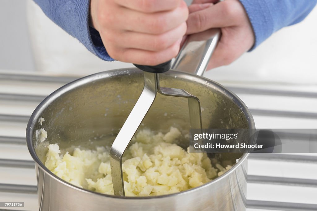 Mashing potato in a pan, close up