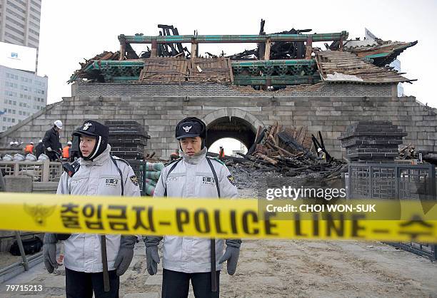 South Korean policemen stand guard in front of the destroyed Namdaemun gate following a fire in central Seoul on February 12, 2008. A man who...