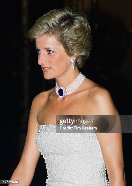 Princess Diana wearing a white strapless dress, embroidered with pearls, designed by Catherine Walker for a banquet during her official visit to...