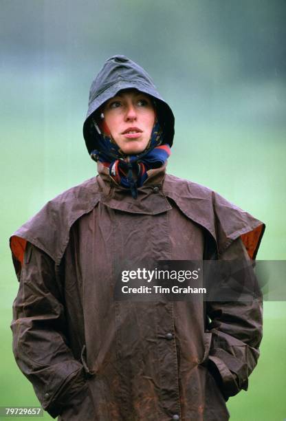 Princess Anne dressed in a Barbour style coat and waterproof hat in the rain at Windsor Horse Trials