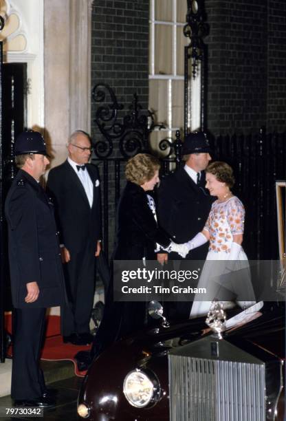 The Prime Minister Margaret Thatcher shakes hands with Queen Elizabeth II outside 10 Downing Street, Her husband Dennis Thatcher is standing behind