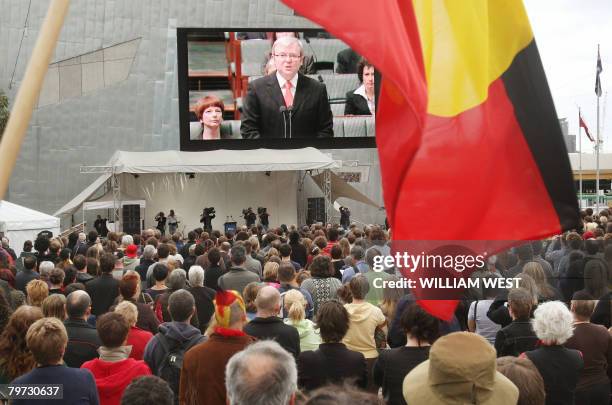 An Aboriginal flag waves in front of the giant television screen as thousands gather in Melbourne's Federation Square on February 13, 2008 to listen...