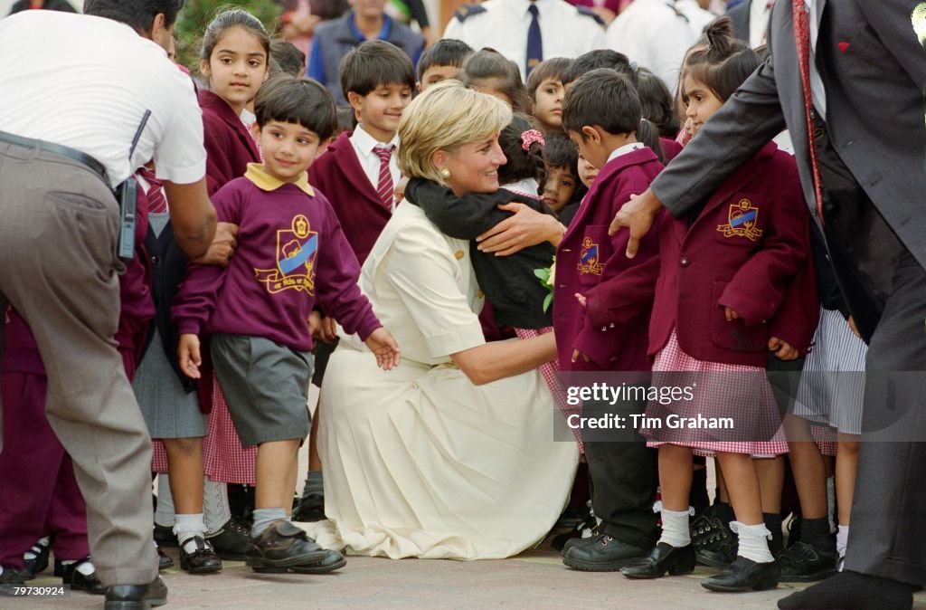 Diana, Princess of Wales crouching down to embrace a pupil a