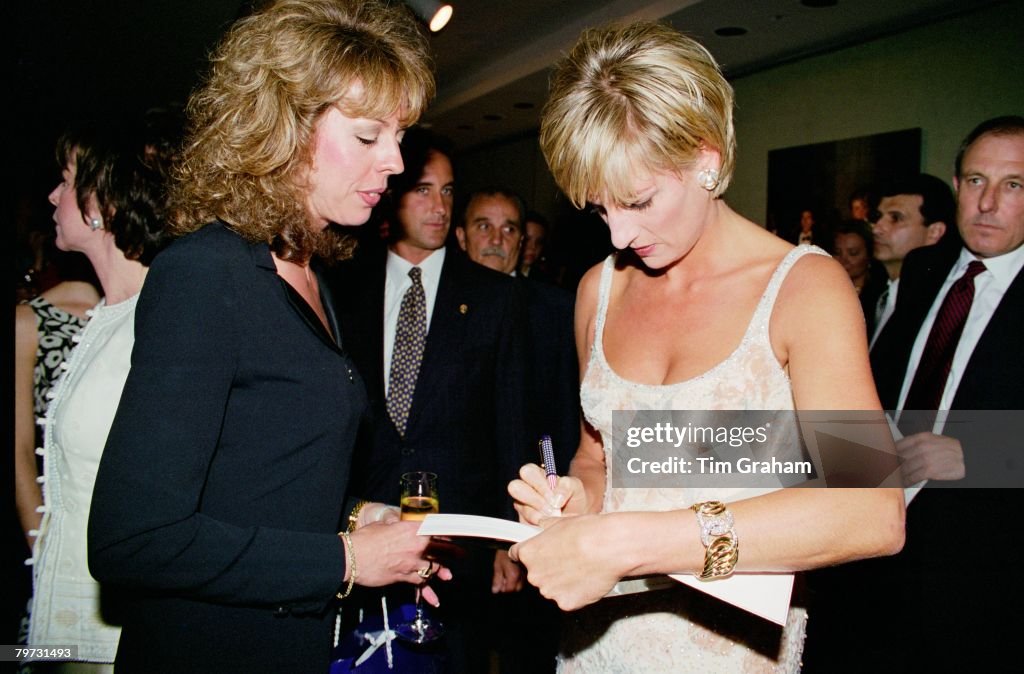 Diana, Princess of Wales signs a book for one of the guests