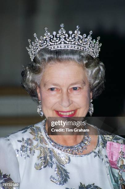 Queen Elizabeth II attends a banquet in Paris wearing a white evening dress embroidered with silver by designer Ian Thomas, the Queen Mary's Girls of...