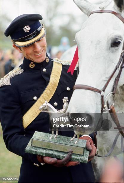 Mark Phillips holds an eventing trophy and stands with his horse 'Columbus'