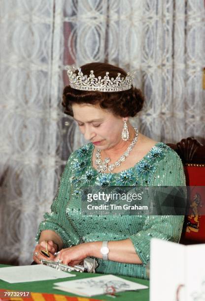 Queen Elizabeth II looks through her handbag during a banquet in Kenya
