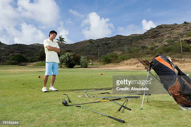 young man looking down at scatter clubs on golf course - sport venue stock pictures, royalty-free photos & images