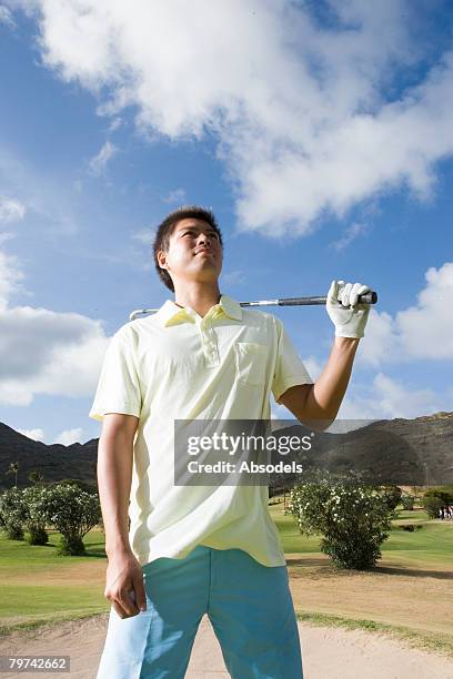 young man standing holding golf club over shoulder, vertical - golf bunker low angle stock pictures, royalty-free photos & images