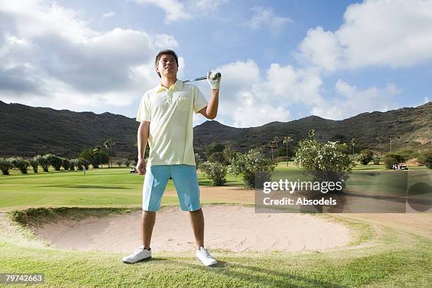 young man standing holding golf club over shoulder, horizontal - golf bunker low angle stock pictures, royalty-free photos & images