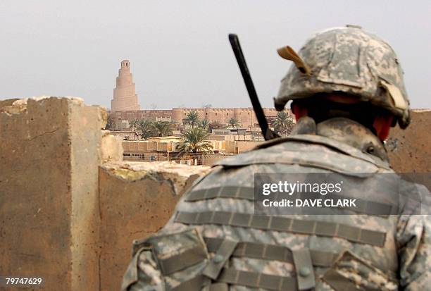 Infantryman takes cover as he keeps watch across the rooftops of the Iraqi city of Samarra on February 11, 2008. Appearing in the background is the...