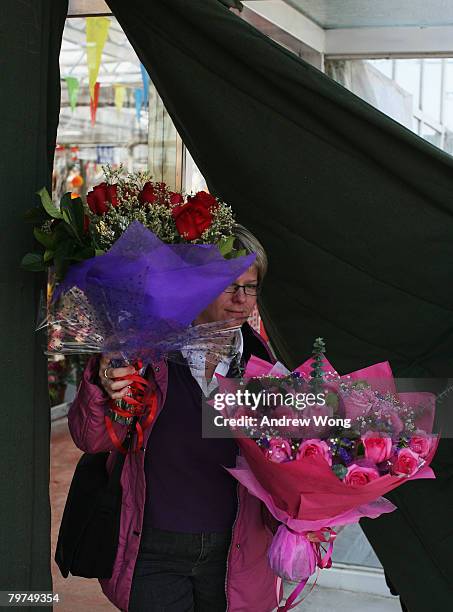 Woman emerges with bouquets of roses from a flower market on Valentine's day February 14, 2008 in Beijing, China. Valentine's Day has become one of...