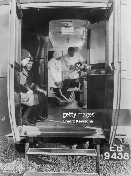 Dentist treats a young girl in a mobile dental surgery operated for the benefit of local schoolchildren by the Isle of Ely County Council in...