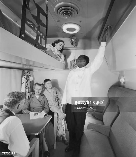 Railroad steward and a family in one of the drawing rooms of a sleeping car manufactured by General Motors and displayed as part of a 'Train Of...