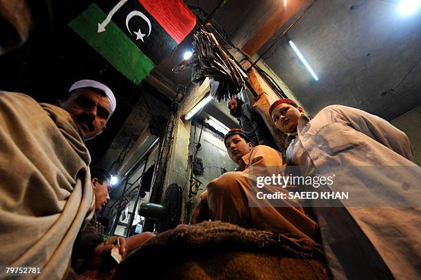 Residents gather at a bread shop decorated with the flag of slain Pakistan former premier Banzir Bhutto's party in the historical Kissa Khawani...