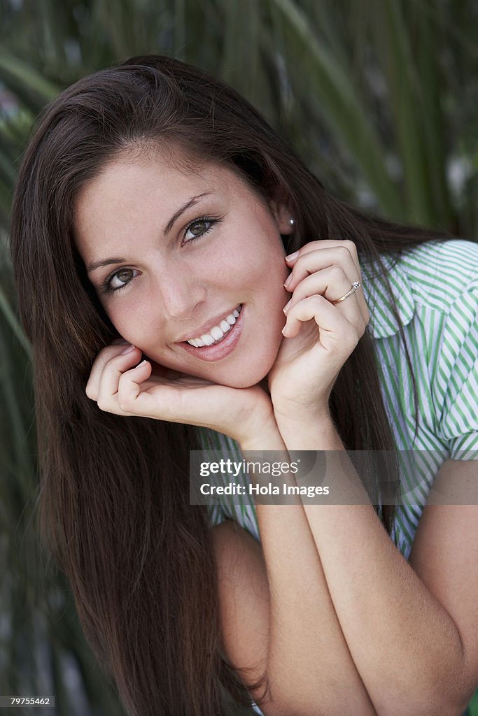 Portrait of a young woman smiling with her hands on her chin