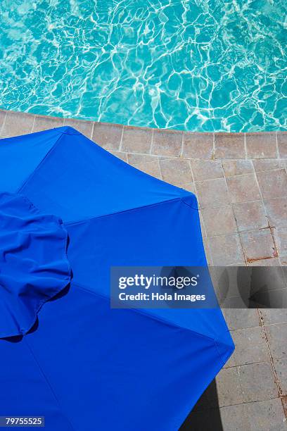 high angle view of a patio umbrella at the poolside - gartenschirm stock-fotos und bilder