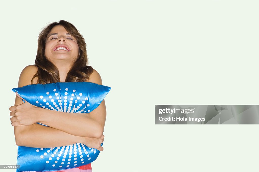 Young woman hugging a cushion and smiling