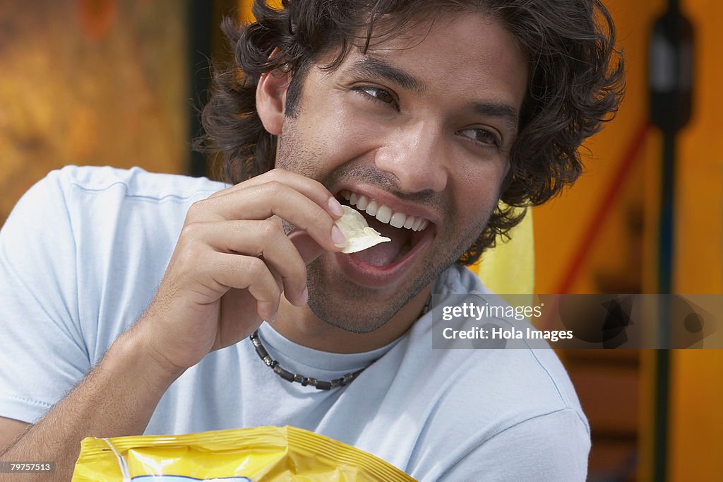 Close-up of a young man eating potato chips