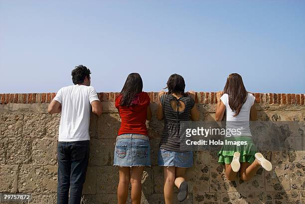 rear view of three young women and a young man looking over a stone wall, morro castle, old san juan, san juan, puerto rico - old san juan wall stock pictures, royalty-free photos & images