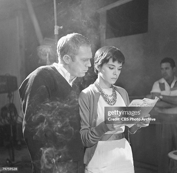 American actor Steve McQueen reads a newspaper over the shoulder of his wife, Philippine-born actress Neile Adams, during the filming of an episode...