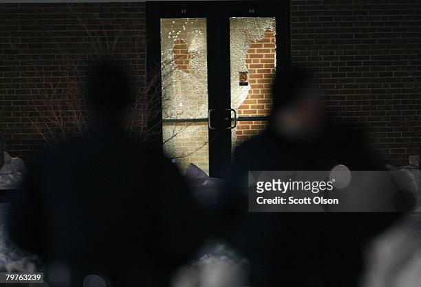 Glass on a door is broken where police are patroling outside Cole Hall following a shooting on the Northern Illinois University campus February 14,...