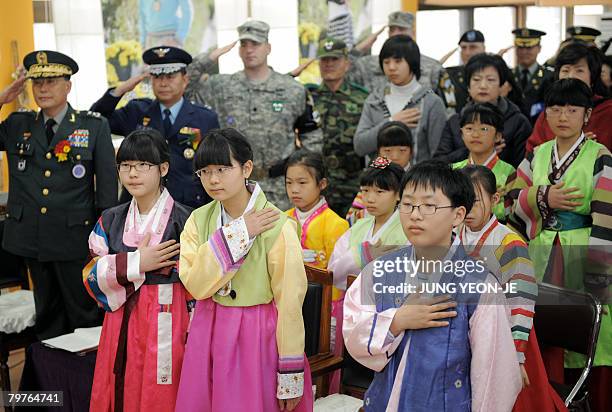 South Korean students from Taesungdong Elementary School and United Nations Command officers salute the national flag during a graduation ceremony in...