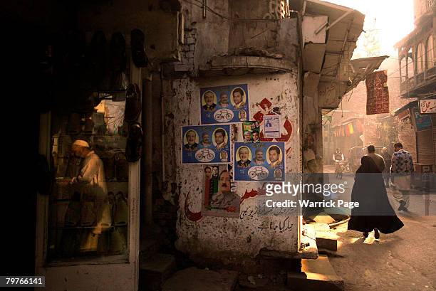 Woman in burqa walks past election posters February 15, 2008 in Lahore, Pakistan. Pakistani national elections will take place next week after months...