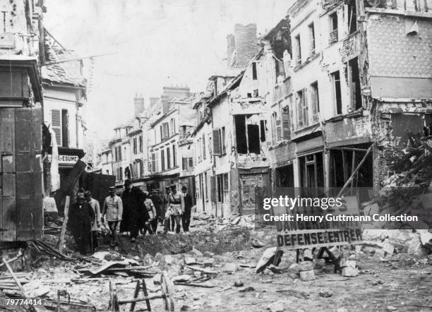 French Prime Minister Georges Clemenceau picks his way through the rubble of a French town towards the end of World War I, 1918. A sign at the end of...