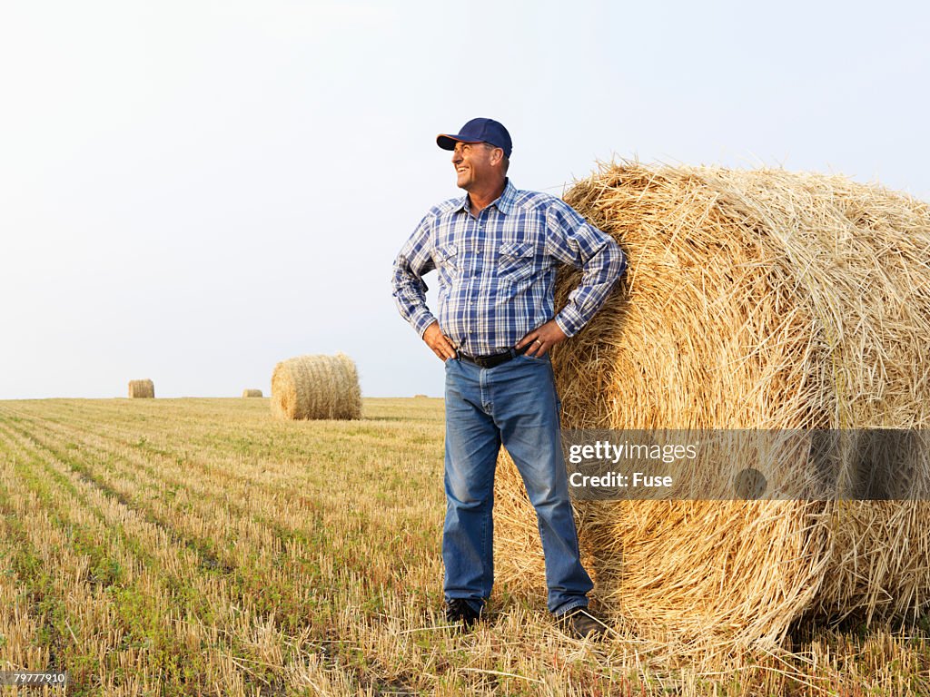 Man Standing by Bale of Hay