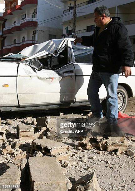 Lebanese man look at his vehicle damaged by falling debris following an earth tremor in the southern Lebanese city of Tyre on February 15, 2008. An...
