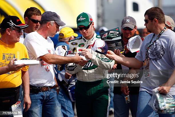 Dale Earnhardt Jr., driver of the Mountian Dew AMP/National Guard Chevrolet, signs autographs for fans during practice for the Daytona 500 at Daytona...