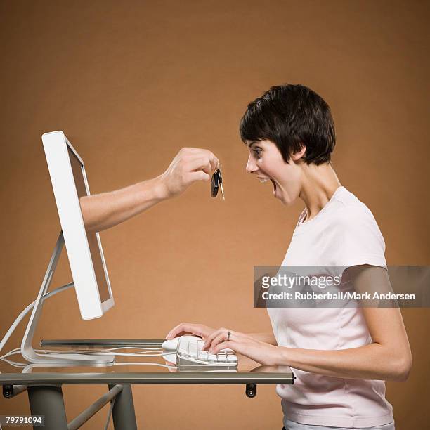 woman sitting at computer with hand emerging from monitor holding car keys - car keys hand ストックフォトと画像