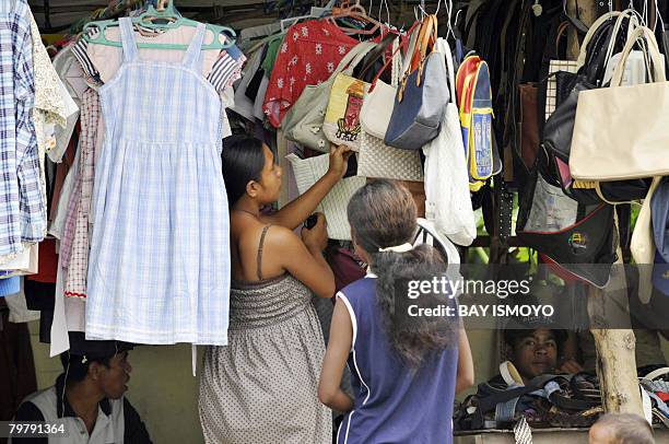 East Timorese women browse for second hand clothes and bags at a sidewalk stall in Dili on February 16, 2008. East Timor has been under a state of...