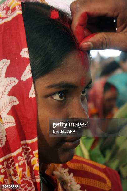 An Indian tribal bride is anointed by her groom as they take part in a mass marriage ceremony during a religious conference in Siliguri on February...