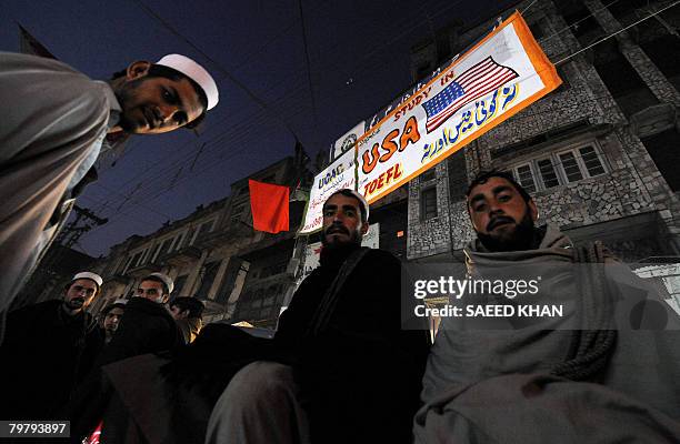 In this picture taken in Peshawar on February 14, 2008 laborers wait for late evening work while sitting under a banner announcing "Study in USA, no...