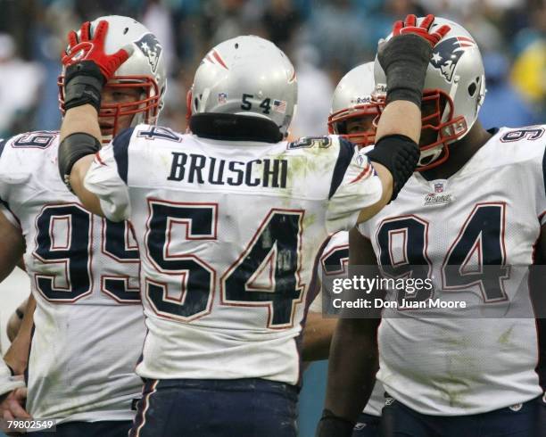 New England ILB Tedy Bruschi, center, places his hands over the helmets of teammates OLB Tully Banta-Cain, left, and LE#94 Ty Warren, right, against...
