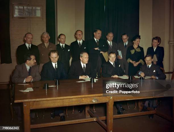 View of the Representatives of the Four Powers seated at a desk to sign the Nuremberg Charter, the agreement that sets down the rules and procedures...