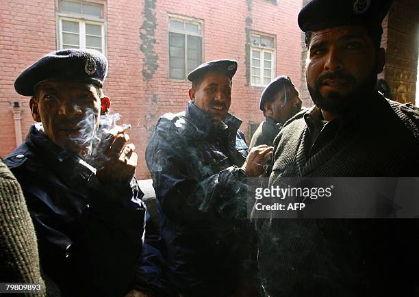 Pakistani policemen smoke at an election material distribution station in Lahore on February 17 a day before the country's general elections....
