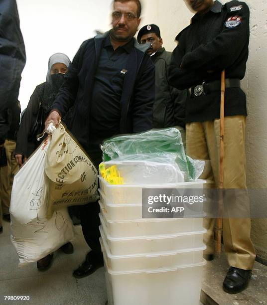 Pakistani man carries the ballot boxes and the bags of election material at a distribution station in Lahore on February 17 a day before the...